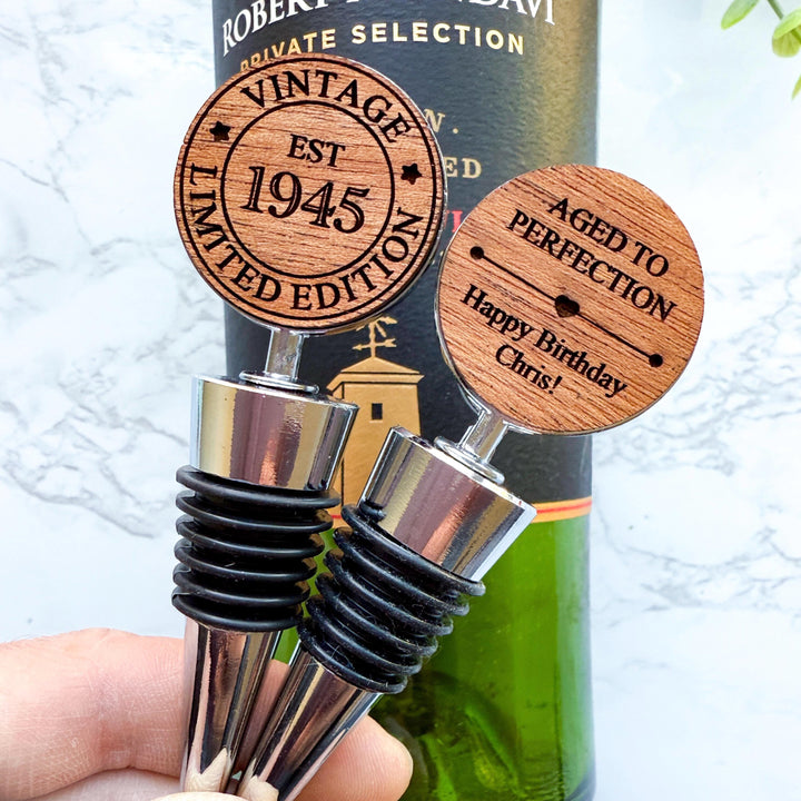 Personalized double sided wooden wine stoppers for a 80th birthday displayed in front of a wine bottle. Perfect custom gift for milestone birthday and wine enthusiasts.