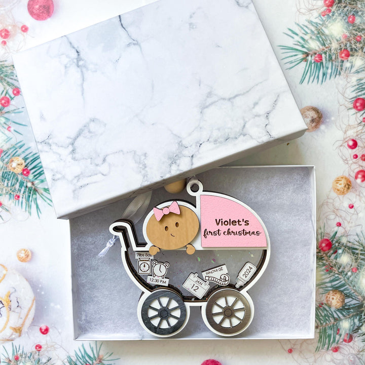 Baby girl first Christmas ornament in carriage design, customizable with baby name and birth stats in a gift box