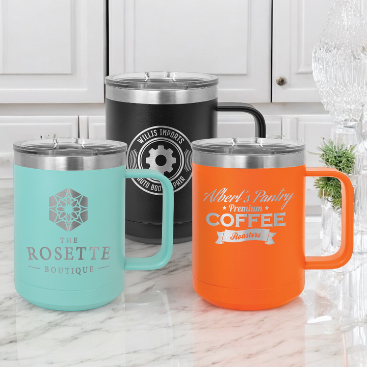 Custom 15oz vacuum insulated stainless steel mugs with slider lids displayed on a marble countertop. The mugs feature custom logos and designs.  Perfect for corporate branding, promotional gifts, or personalized drinkware.