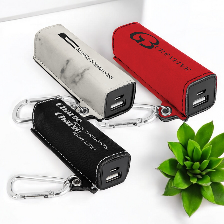 Custom laser-engraved leatherette 2200mAh power bank with silver carabiner and USB cord, ideal for corporate branding and promotional gifts.