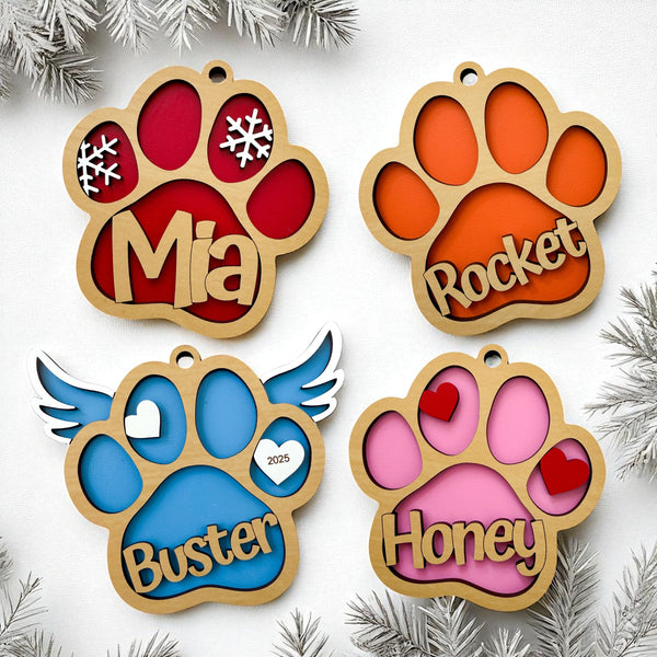 Personalized paw print ornaments with custom pet names in four styles, Classic Paw, Snowflake Paw, Heart Paw, and Angel Wings Paw, available in eight colors including purple, light blue, blue, lime green, pink, red, orange, and yellow.
