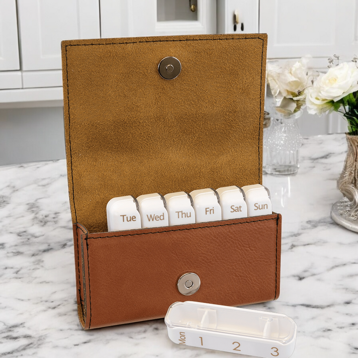 Close-up view of a rawhide leatherette weekly pill organizer featuring a magnetic snap closure. Includes labeled daily containers with three compartments for easy medication management. Stylish and practical for personal use or corporate healthcare branding.